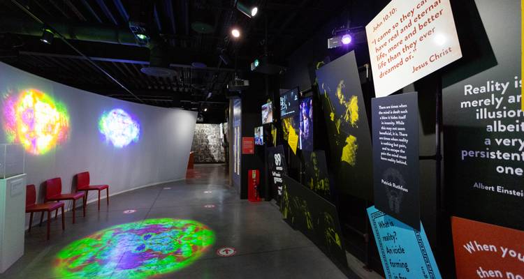 Modern museum corridor with colorful projected lights and inspirational quote panels lining dark walls.