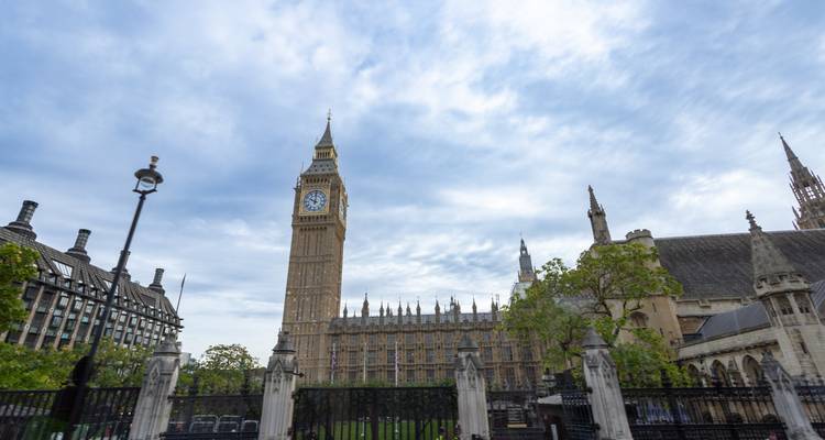 Iconic Big Ben clock tower and the Houses of Parliament rising against a partly cloudy sky in London.