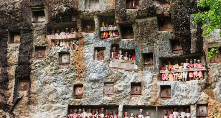 Sitio de entierro en acantilados rocosos con balcones de efigie de madera y nichos ahuecados del pueblo Toraja.