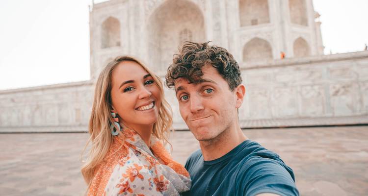 Couple posing in front of a landmark with intricate stonework.