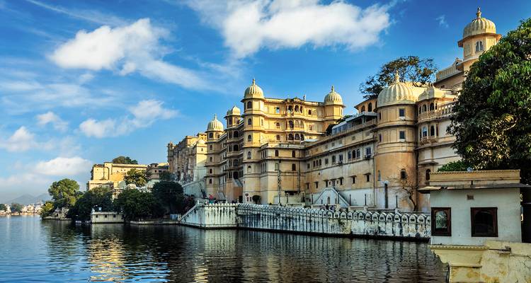 A beautiful lakeside palace with a view of the sky reflecting in the water.