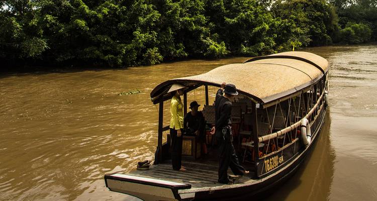 Traditional boat on a river with people standing on board.