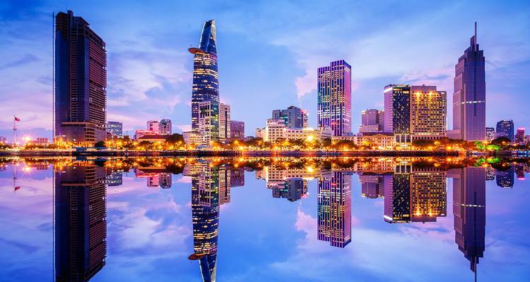 Die lebendige Skyline von Ho-Chi-Minh-Stadt spiegelt sich makellos im Saigon-Fluss wider, während Dämmerunglichter über modernen Wolkenkratzern funkeln.