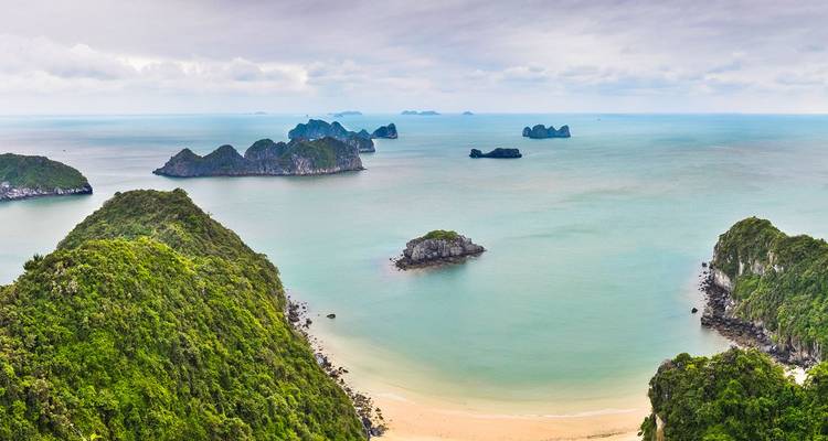 Vue panoramique depuis un point de vue élevé sur des îles émeraude et une mer turquoise avec une plage de sable en dessous.