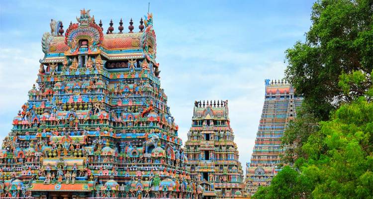 Colorful gopurams of an Indian temple with trees.