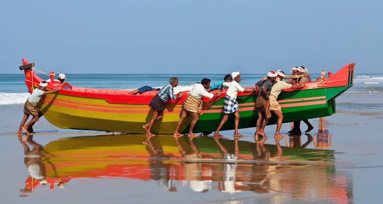 People launching a colorful fishing boat