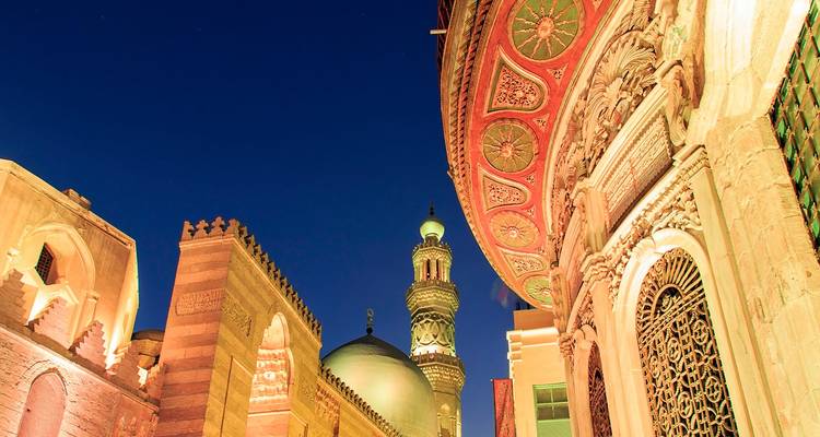 Los minaretes y domos ornamentados de El Cairo Islámico brillan contra un profundo cielo nocturno.