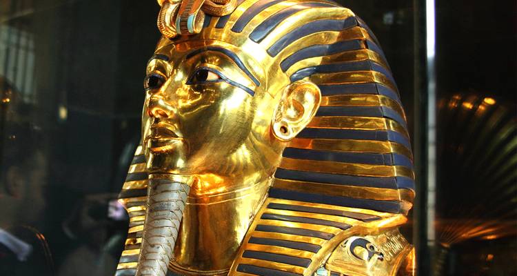 Masque doré d'un pharaon de l'Égypte antique exposé dans un musée.