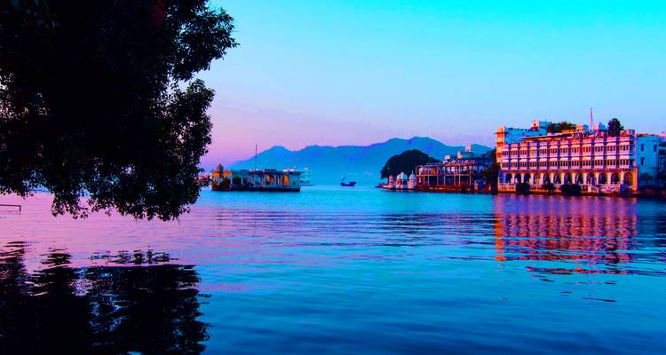 Lago al atardecer con edificios a lo largo de la orilla.