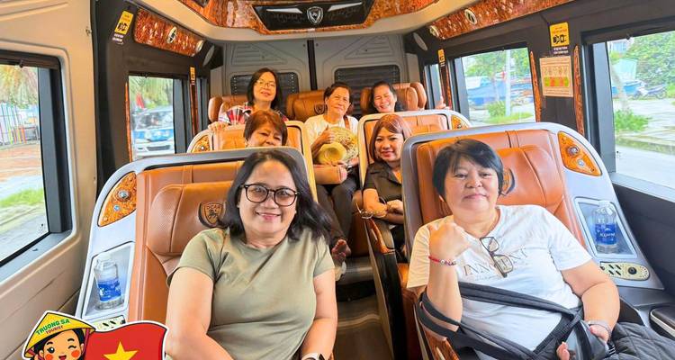 Seven travelers seated comfortably inside a modern minivan with tan leather seats, smiling toward the camera.
