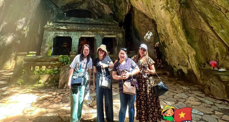 Four women posing inside a limestone cave temple with rugged walls and filtered sunlight.