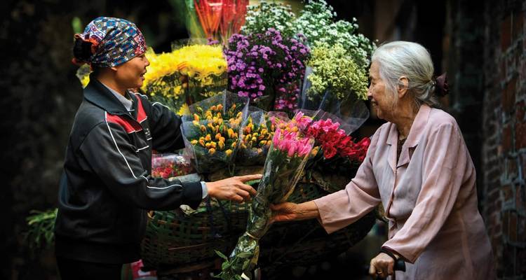 Two people exchanging flowers at a market.