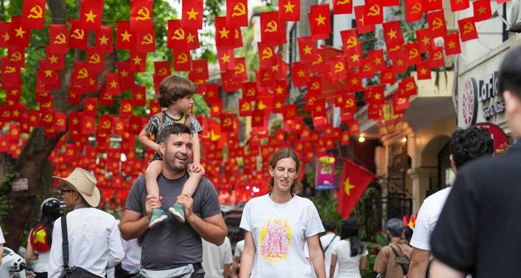 Street filled with Vietnamese flags and pedestrians.