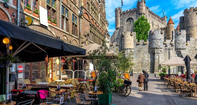 Scène extérieure avec un château et un café au premier plan.