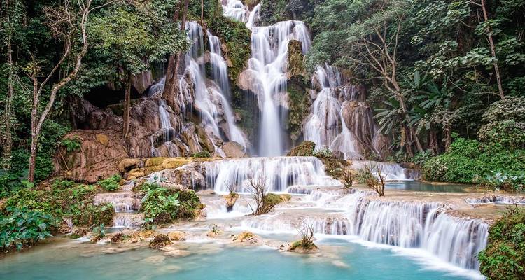 Hermosa cascada que cae en cascada hacia piscinas turquesas rodeadas de exuberante vegetación.