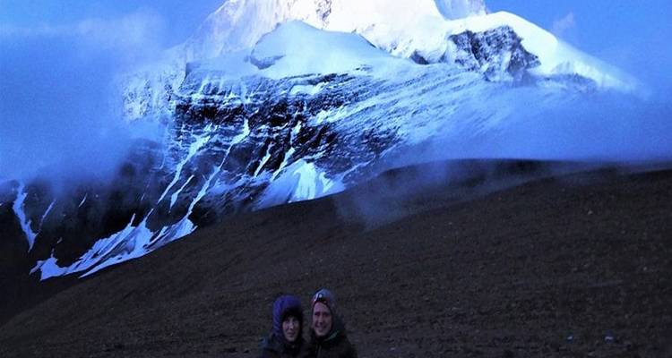 Deux personnes debout avec un arrière-plan de montagne enneigée.