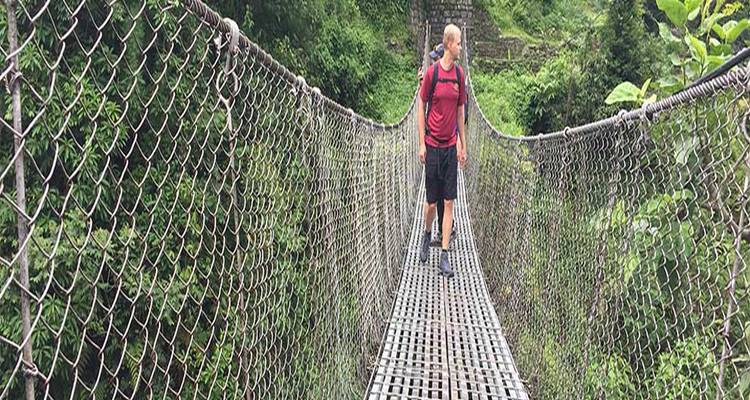 Randonneur traversant un pont suspendu dans une forêt.
