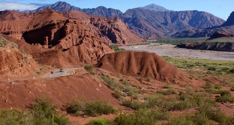 Lebhafte rote Felsformationen mit einer fernen Straße in einem bergigen Gebiet.