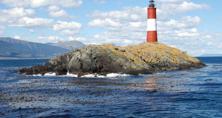 Leuchtturm auf einer felsigen Insel, umgeben von Meereswellen.