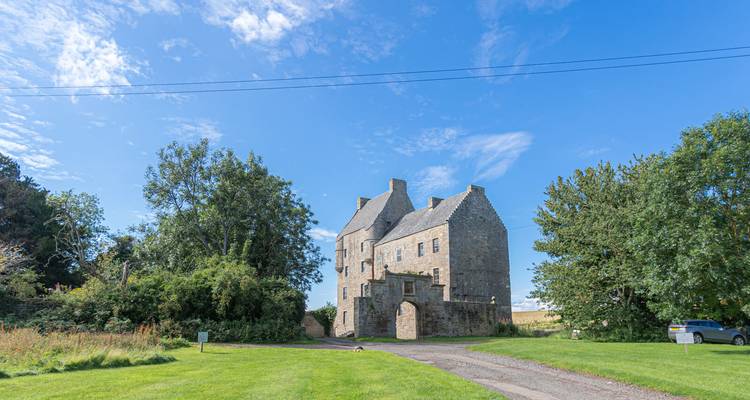 Ein mittelalterliches Steingebäude umgeben von einer üppigen grünen Landschaft.