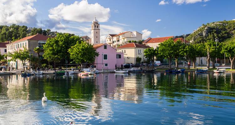Des bâtiments colorés se reflétant dans un port calme.