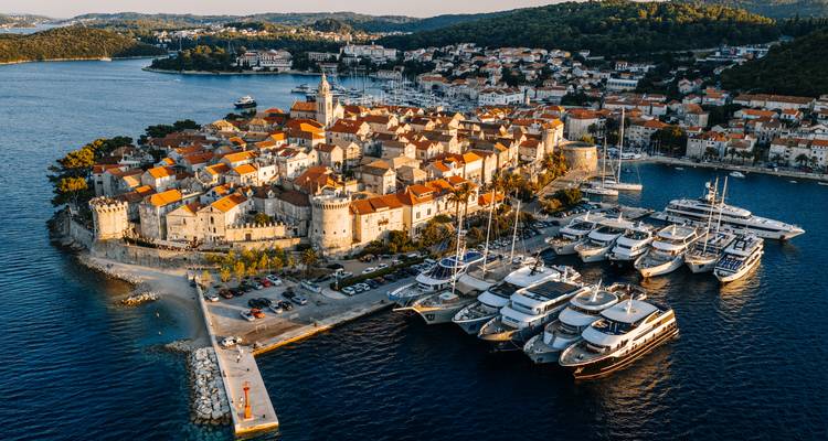 Old fortified town with modern marina and yachts in view.