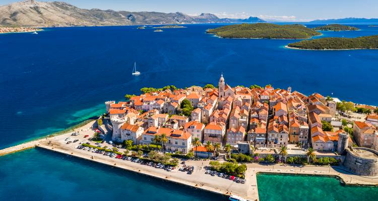 Aerial view of a medieval town on an island with clear blue seas.