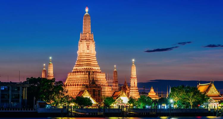 Verlicht Wat Arun tempelcomplex in de schemering reflecterend over de Chao Phraya rivier.
