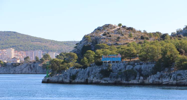 Ladera costera con árboles y edificios distantes.
