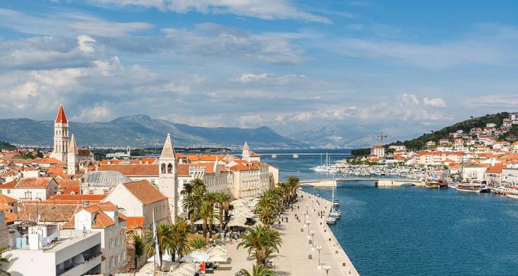 Vista panorámica de un pueblo costero con tejados naranjas y un mar azul cristalino.