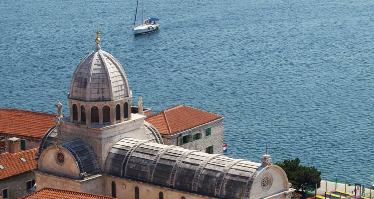 Primer plano de una cúpula histórica cerca de una gran masa de agua con un velero.