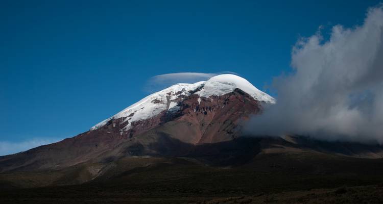 Pic volcanique enneigé avec un ciel bleu dégagé.