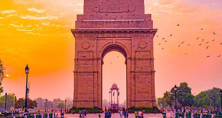 People walking near India Gate during sunrise.