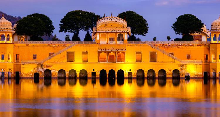 Palacio iluminado reflejándose en un lago tranquilo al anochecer.