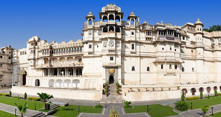 Panorama of a large, historic palace with manicured gardens.