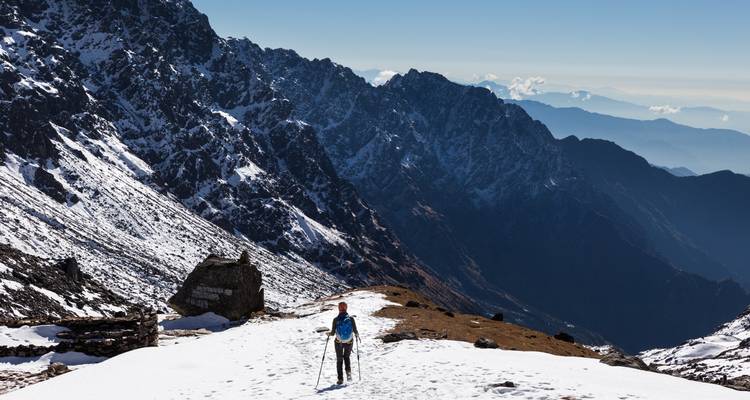 Einzelwanderer auf einem Bergpfad mit weitläufiger Aussicht.