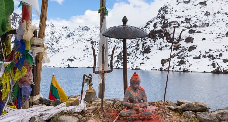 Religiöser Schrein an einem See mit schneebedeckten Gipfeln.