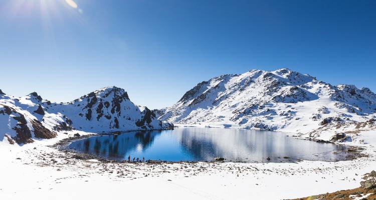 Gefrorener See umgeben von schneebedeckten Bergen unter klarem blauen Himmel.