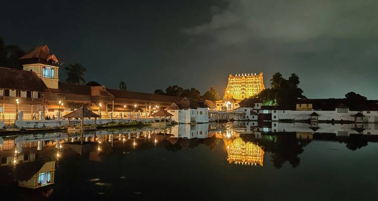 Padmanabhaswamy Temple lit up at night with reflective waters.