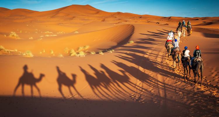 Gente montando camellos a través de las arenas del desierto.