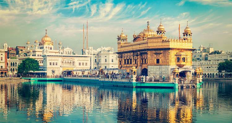 Bâtiment de temple doré avec reflet dans l'eau sous un ciel bleu.