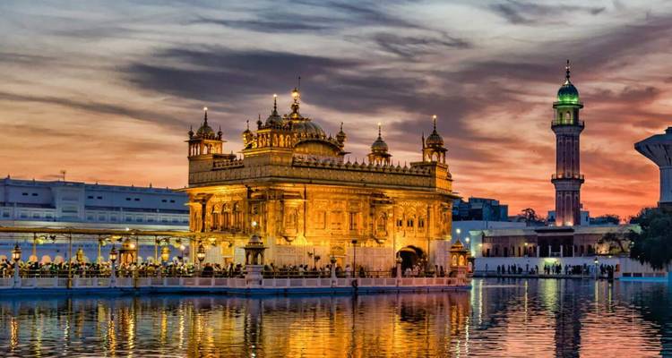 Bâtiment de temple doré illuminé au coucher du soleil.