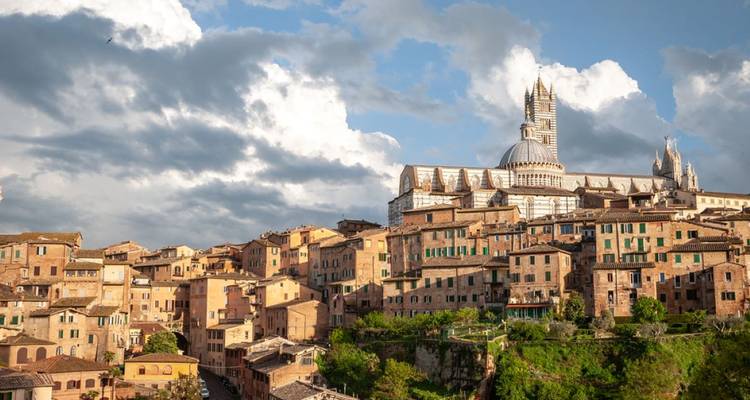 A picturesque town with historic buildings and a cathedral under a dramatic sky.