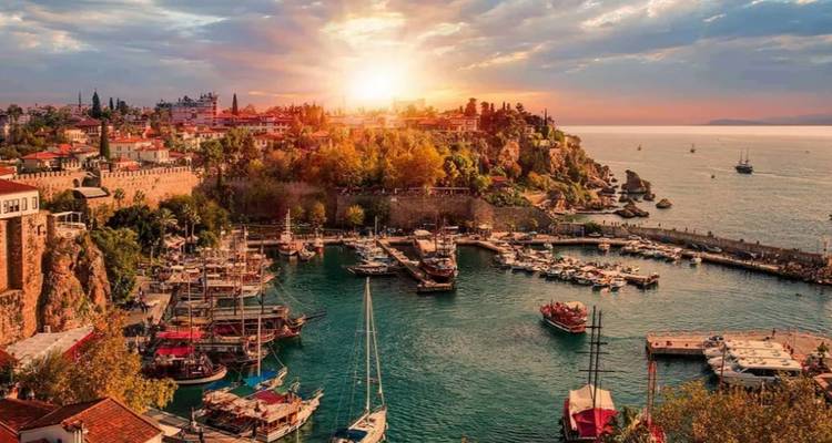 Hafen mit Jachten und einer historischen Skyline bei Sonnenuntergang.