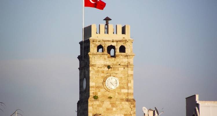 Steinerner Uhrenturm mit der türkischen Flagge.