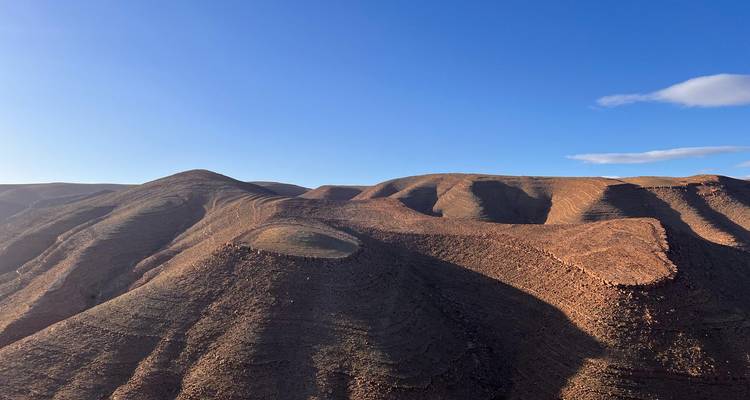 Collines désertiques rocheuses sous un ciel bleu.