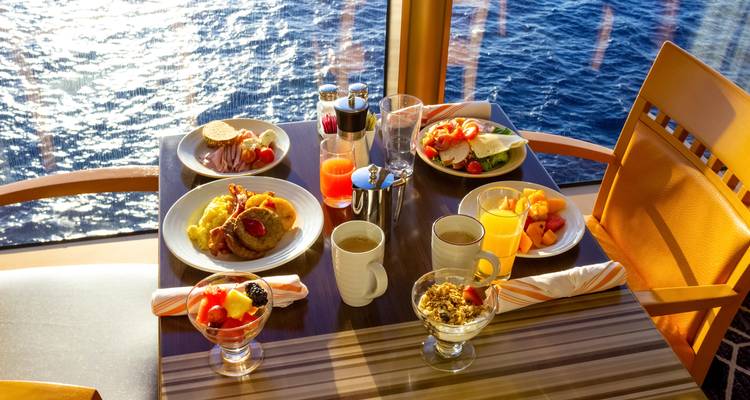 Mesa con una variedad de platos de desayuno con vista al mar.