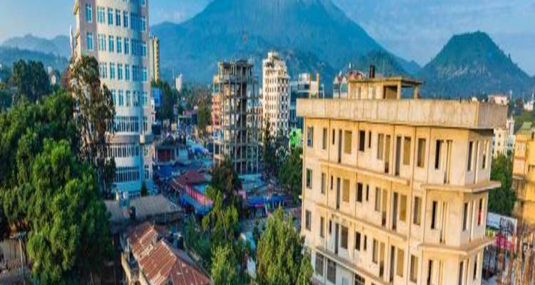 Cityscape with buildings and a mountain in the background.