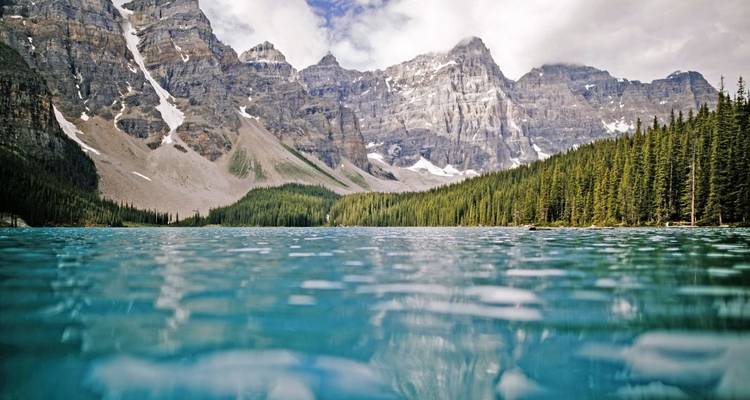 Nahaufnahme eines ruhigen Sees, umgeben von schroffen Bergen.