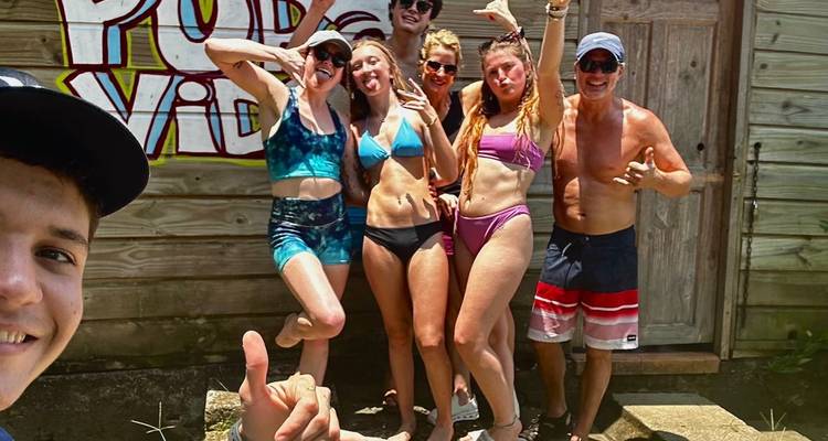 Un groupe de personnes en maillots de bain posant pour une photo devant un mur de graffitis.